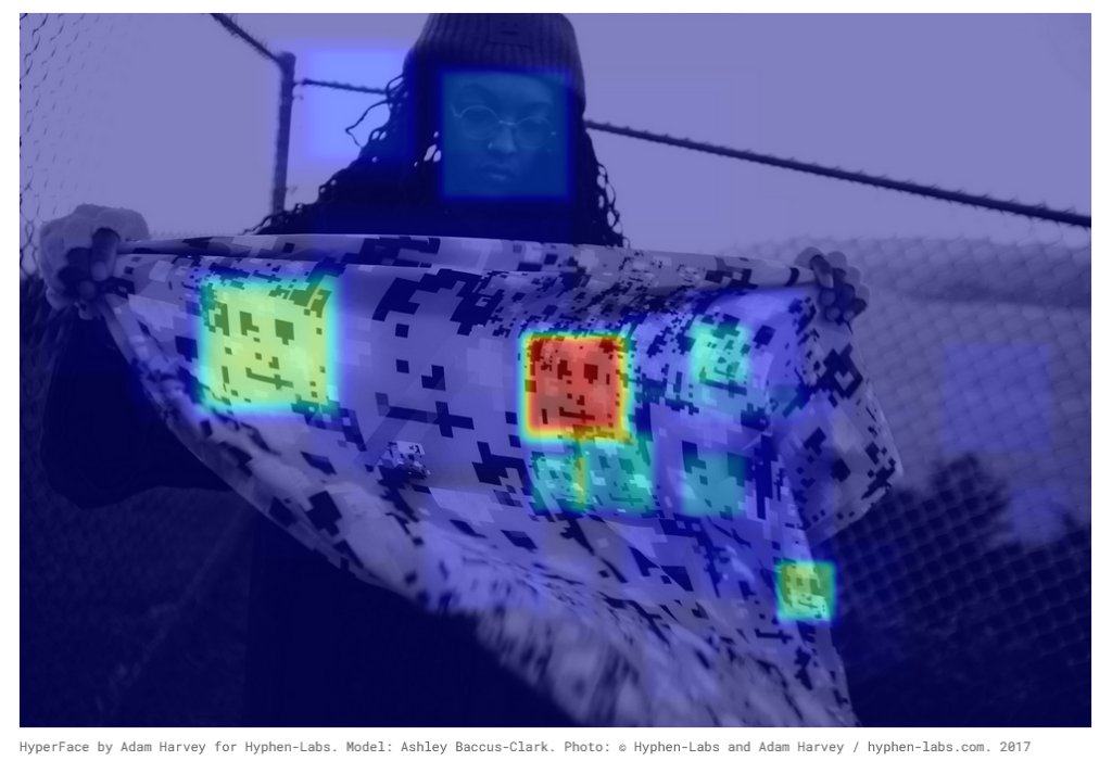image | xy magazine person wearing a beanie and round glasses holds a scarf that shows thermal imagery with colored blocks red green and a blue overlay